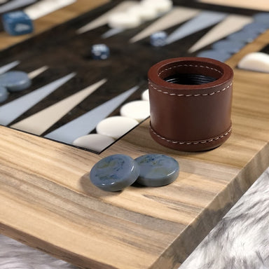 luxury backgammon board in wood and leather with gray and white checkers close up view of brown cup and gray checkers